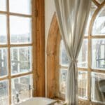 From above of bathtub in light bathroom with big shabby windows in vintage interior